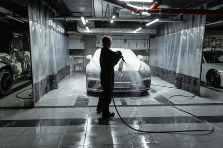 Person detailing luxury car with foam spray in modern garage, LynXautoinnovate automotive parts