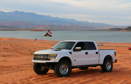 White Ford pickup truck in desert near lake, showcasing off-road automotive parts from LynXautoinnovate USA.
