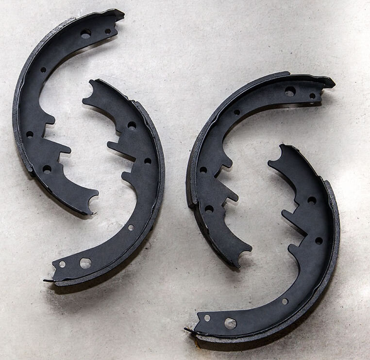 Two black brake shoes on a gray background