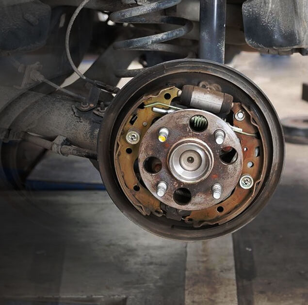 Close-up of a rusted car wheel hub and suspension system.