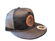 Black mesh cap with leather patch and logo on a textured surface