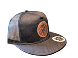 Black mesh cap with leather patch and logo on a textured surface