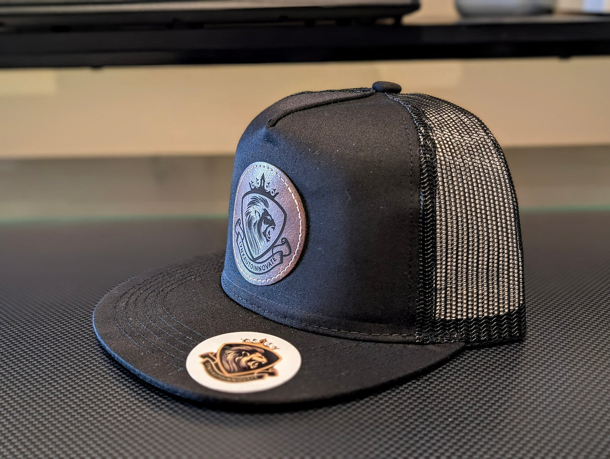 Black trucker cap with mesh back and embroidered logos on a textured surface